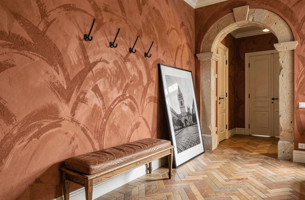 Entrée rénovée avec murs en badigeon terracotta, banc en chêne ancien et voûte en pierre naturelle pour un intérieur chic et caractère maison de maître